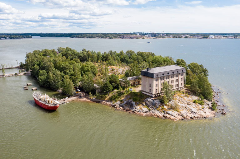 Ilmakuva Hylkysaaresta jossa kasarmirakennus ja rannalla laiva.