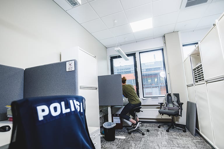 Poliisi työskentelee istuen työtilassa.