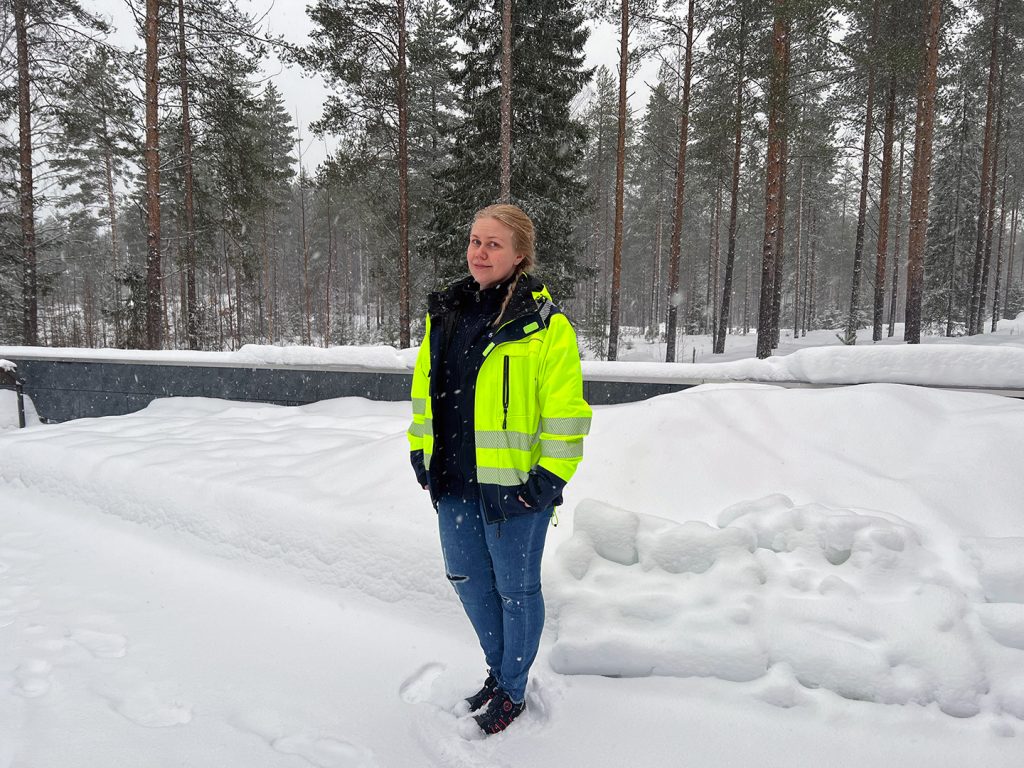 Siivouspäällikkö Päivi Seppänen seisoo talvisessa maisemassa, metsää taustalla.