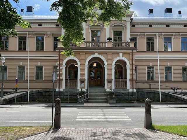Vaalea arvorakennus, jonka sisäänkäynnissä kaarevat yksityiskohdat.