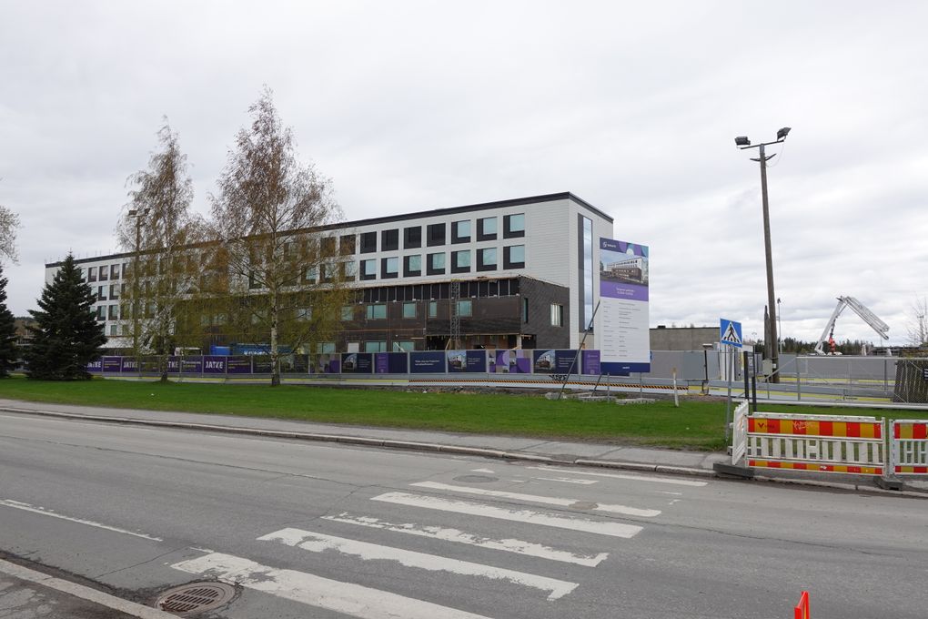 Rakennustyömaa kadun varrella, taustalla suuri rakennus.