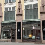 Katunäkymä kivitalosta ja sen liiketilan kahdesta isosta näyteikkunasta.