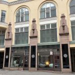 Katunäkymä kivitalosta ja sen liiketilan kahdesta isosta näyteikkunasta.