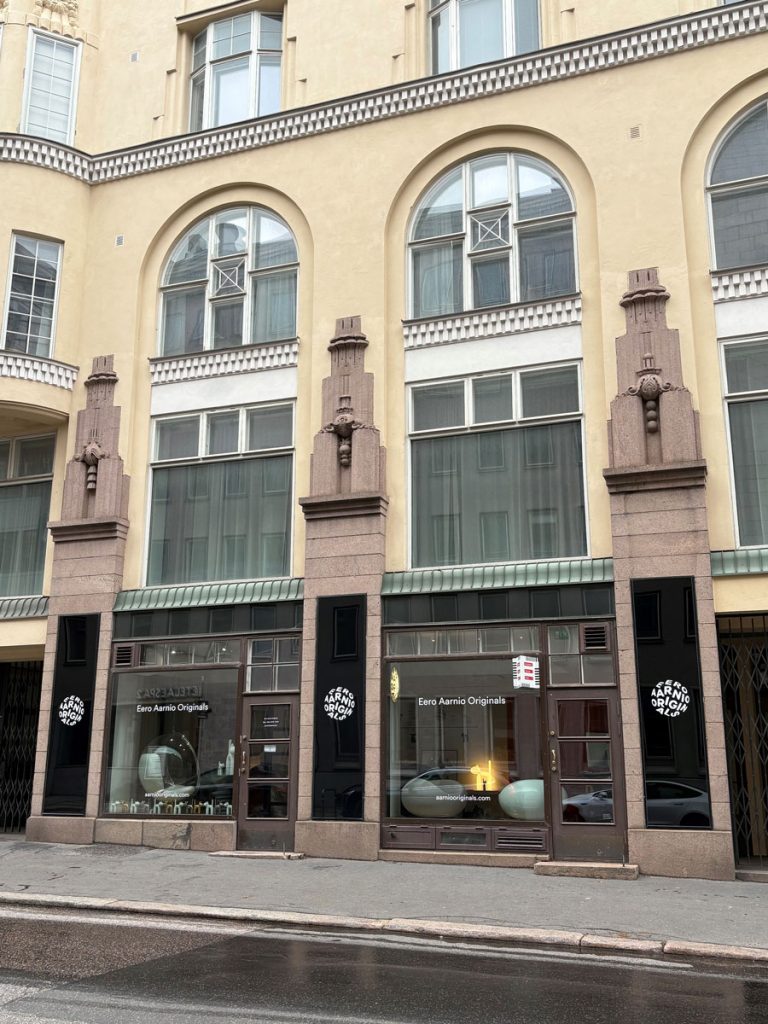 Katunäkymä kivitalosta ja sen liiketilan kahdesta isosta näyteikkunasta.