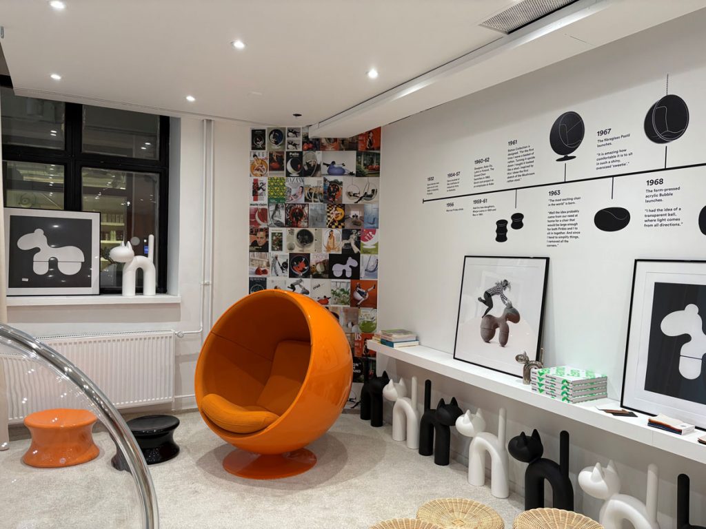 Liiketila takaseinän suuntaan. Seinät on maalattu valkoisella ja sinne on ripustettu esittelymateriaalia. Katossa näkyy valopisteet.