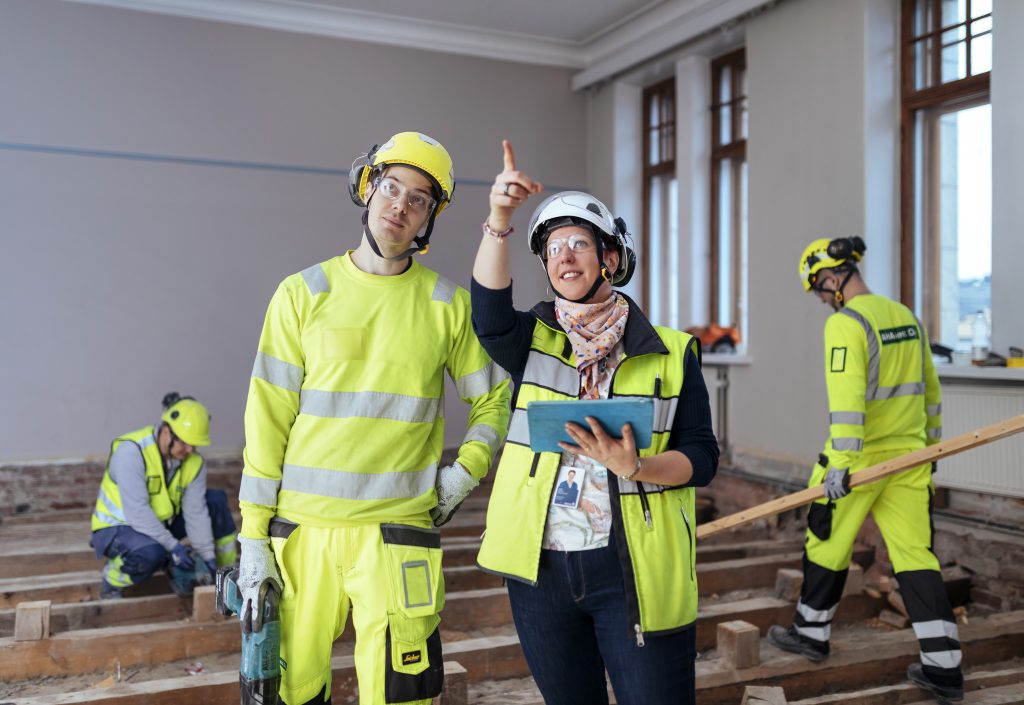 Neljä henkilöä työskentelee rakennustyömaalla.