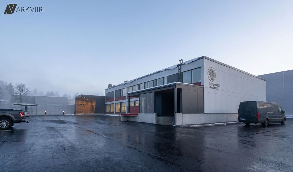 Vaalea rakennus, jonka seinässä lukee sotilaskoti ja uimahalli. Pihalla pysäköityjä ajoneuvoja ja märkä asfalttipiha.  Sumuinen talvimaisema.