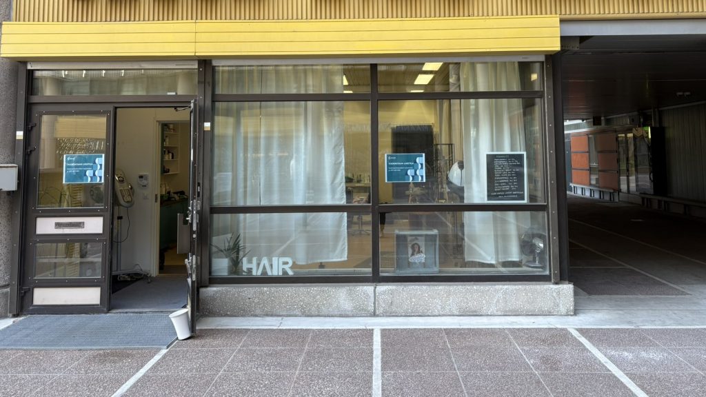 Katunäkymä lasiseinäisestä julkisivusta jossa ulko-ovi auki.
