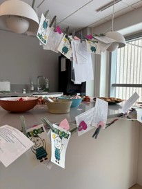 Pyykkinaruun kiinnitettyjä kortteja ja ystävänpäiväherkkuja työkahvilan pöydällä.