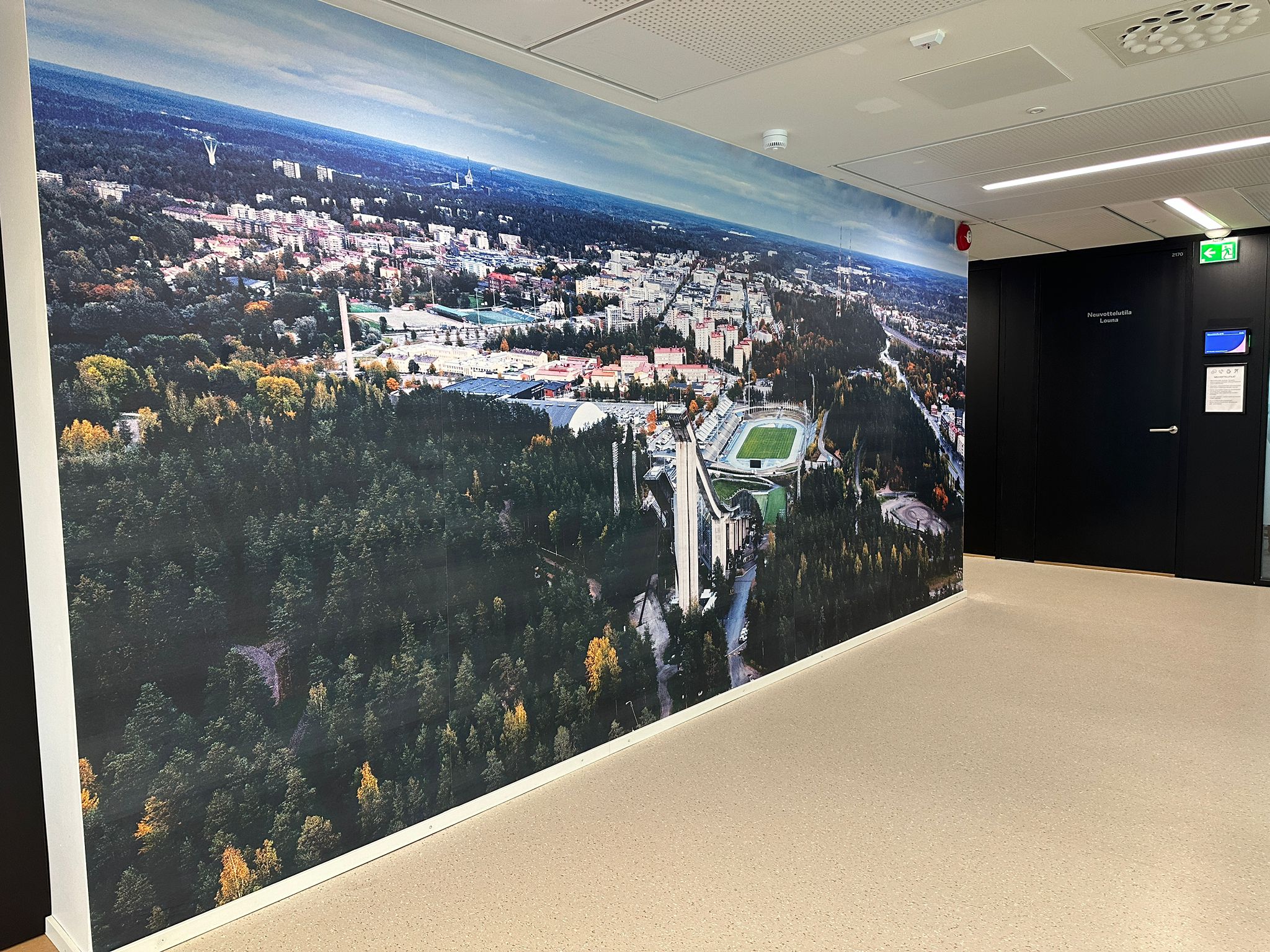 Maisemaseinä toimistossa. Seinässä on ylhäältä päin otettu kuva Lahden kaupungista.