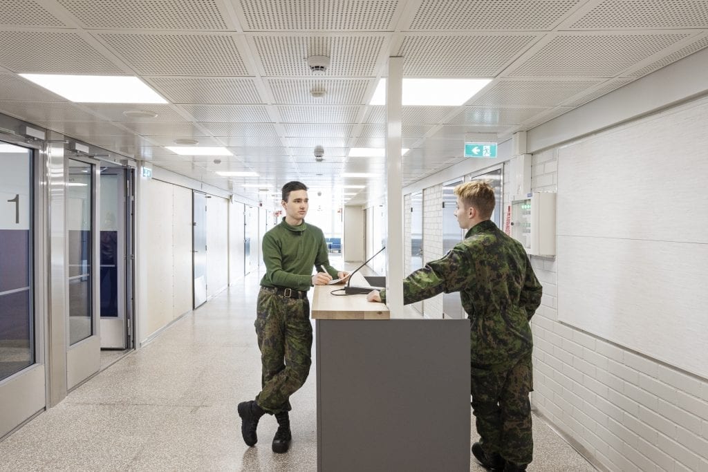 Kaksi henkilöä armeijan vaatteissa keskustelee käytävällä.
